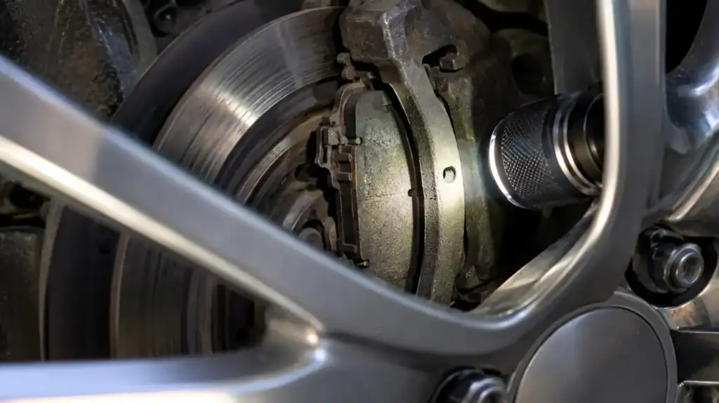 Close-up of brake pad inspection through alloy wheel spokes with visible rotor and caliper